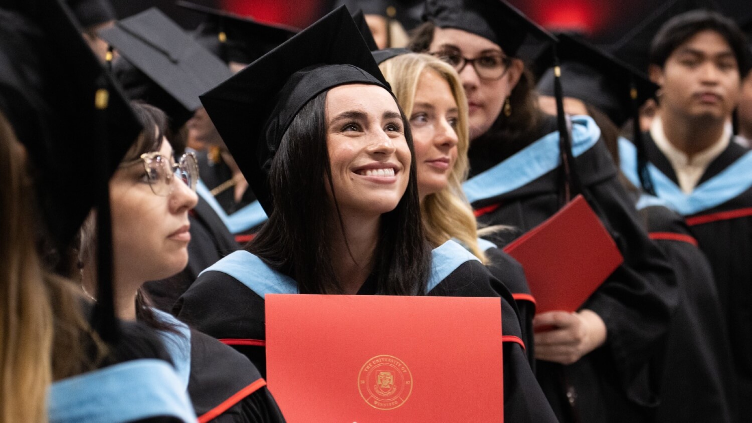 A student smiles while holding a degree at Convocation
